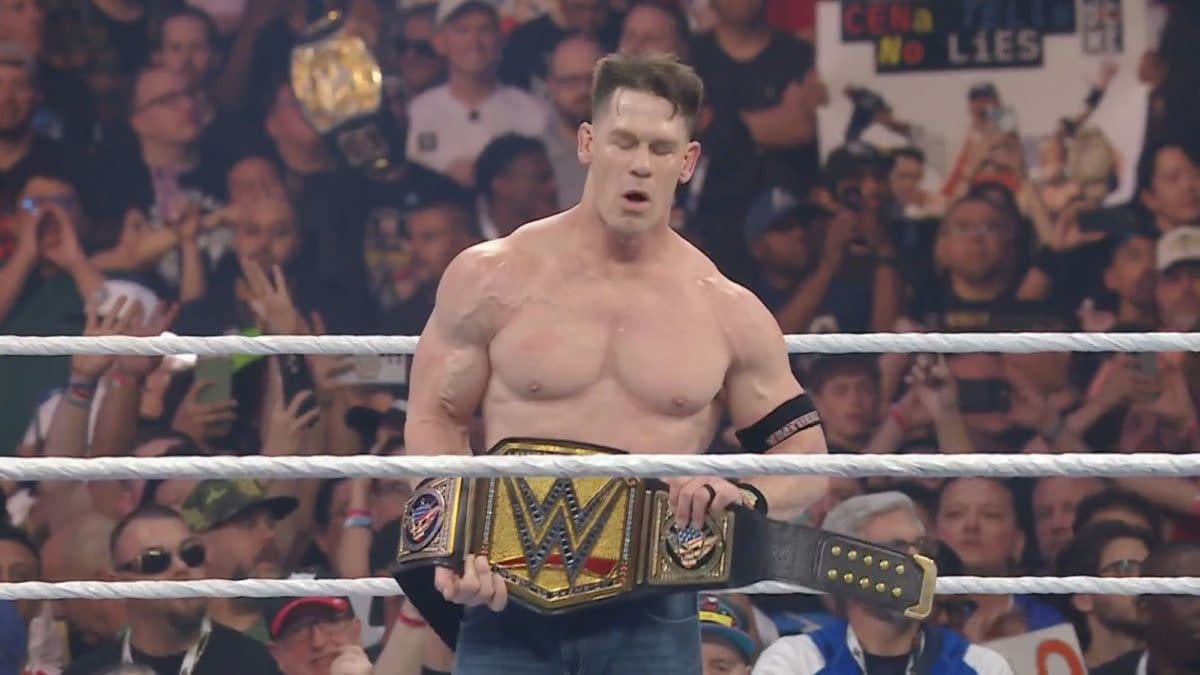 John Cena stands in the wrestling ring holding the WWE championship belt with a look of triumph after defeating Cody Rhodes at WrestleMania 41, surrounded by a cheering crowd.