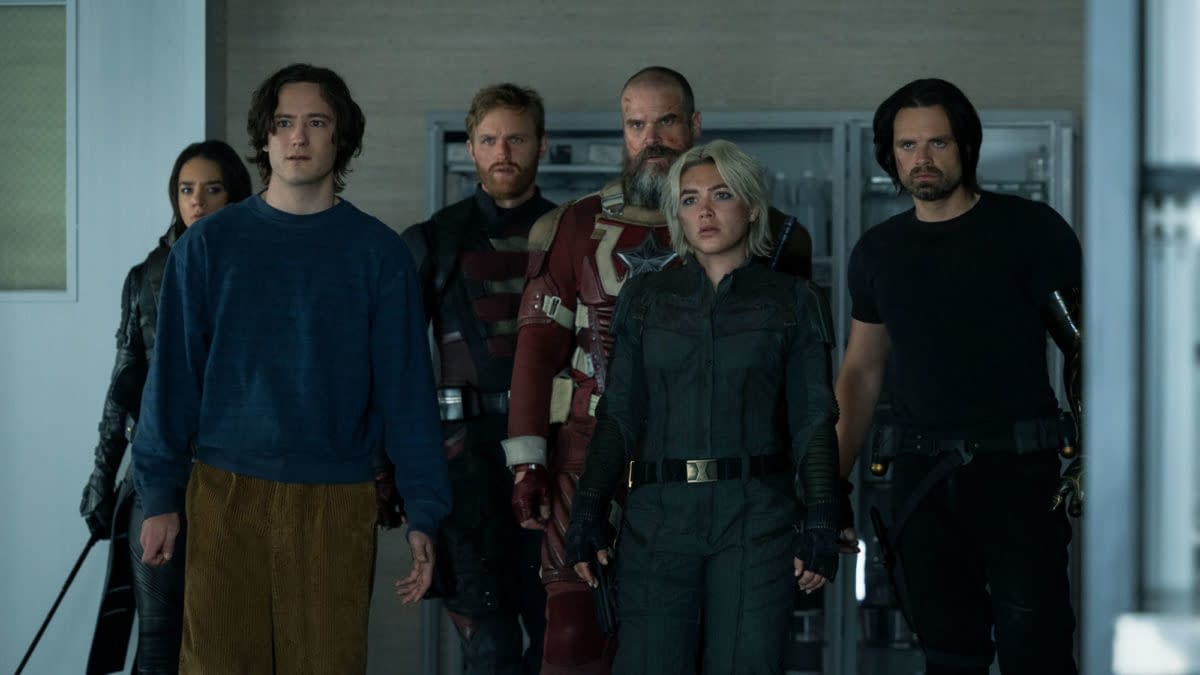 A group of six characters from Marvel Studios' 'Thunderbolts' stands in an indoor setting, showcasing a diverse range of outfits and expressions, highlighting their distinct personas. The characters appear to be united in purpose, creating a sense of tension and anticipation.
