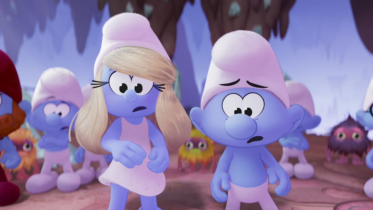 A scene from the animated movie "Smurfs," featuring the characters Smurfette, Brainy Smurf, and Ken. Smurfette has blonde hair and a worried expression, while Brainy Smurf looks concerned, set against a colorful background with other Smurf characters in the scene.