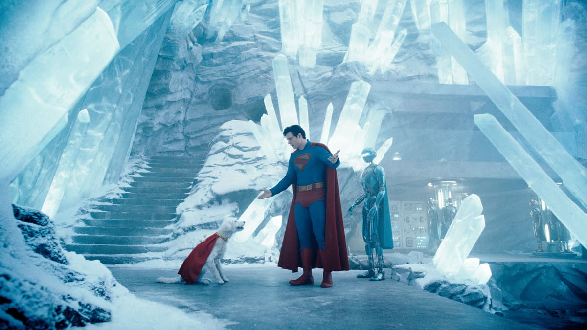 Superman stands in an icy, crystalline environment, interacting with a dog wearing a cape, while a humanoid robot observes nearby. The scene conveys a whimsical mix of superhero and science fiction elements.