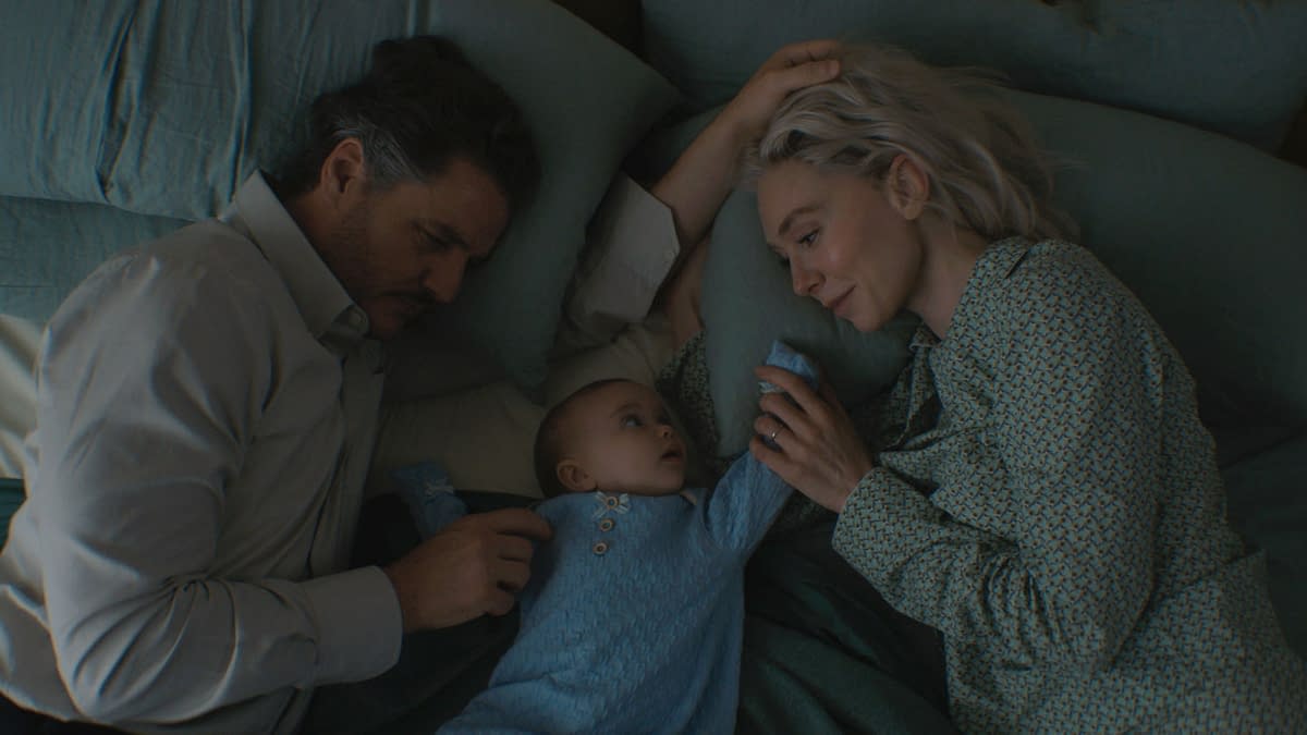 A scene from 'The Fantastic Four: First Steps' featuring characters Reed Richards, played by Pedro Pascal, and Sue Storm, played by Vanessa Kirby, lying on a bed with their baby Franklin Richards. The trio is surrounded by soft pillows and blankets, creating an intimate family moment.