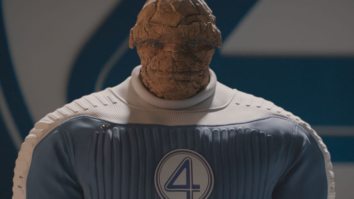 Ebon Moss-Bachrach portrays Ben Grimm, also known as The Thing, in a blue and white superhero suit featuring the number four emblem, from the Marvel Studios film "The Fantastic Four: First Steps." The character has a textured, rocky appearance.