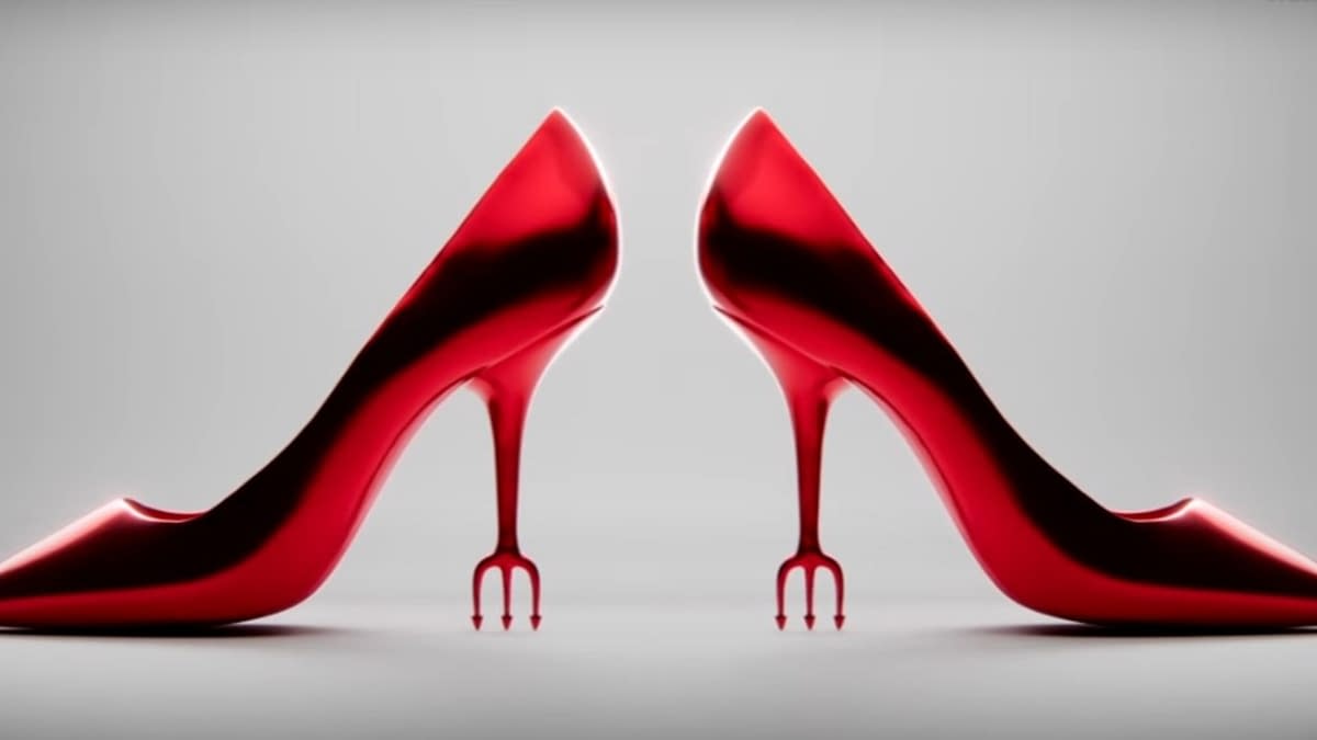 A pair of glossy red high-heeled shoes with unique fork-like heels, highlighted against a neutral backdrop. The design evokes a sense of fashion-forward sophistication and edginess.