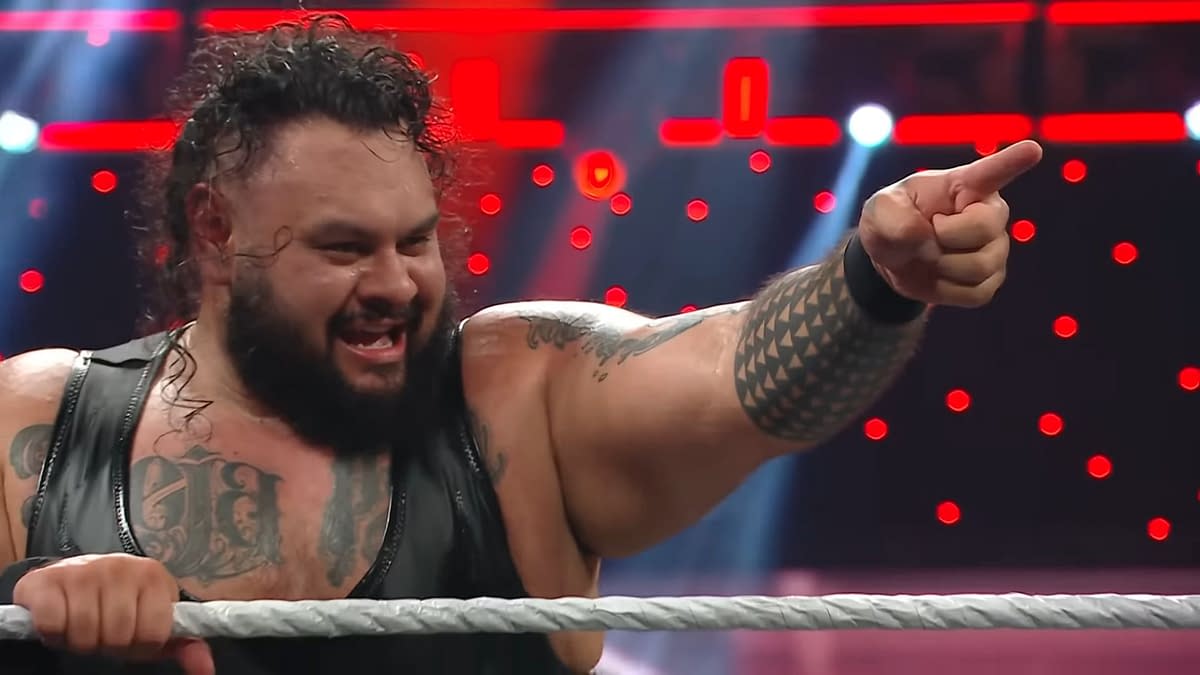 Bronson Reed, a professional wrestler, appears on WWE Raw, passionately pointing while celebrating in the ring. He has long curly hair and visible tattoos on his arms and chest.