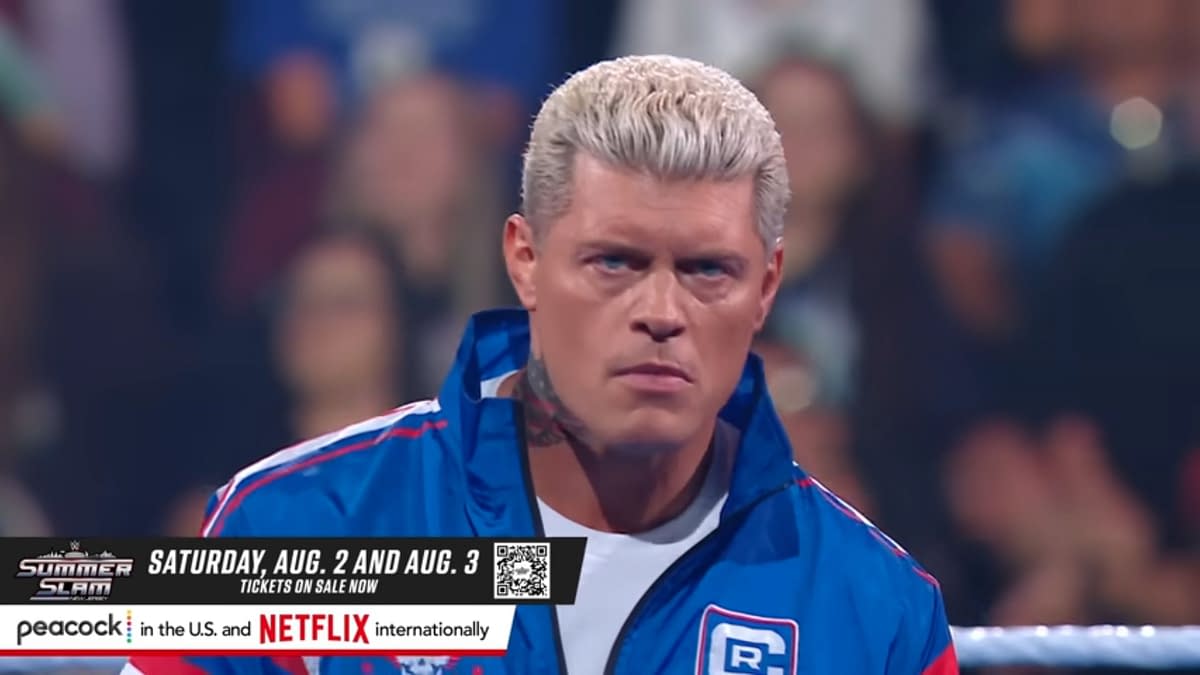 Cody Rhodes, sporting a blue jacket, stares intently while standing in a wrestling ring, with blurry crowd members in the background. The image promotes WWE SummerSlam events on August 2 and August 3, 2025.
