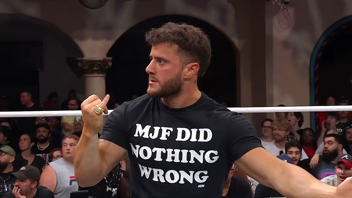 A wrestler wearing a black shirt with the phrase "MJF DID NOTHING WRONG" gestures animatedly while other fans are visible in the background on AEW Dynamite. The scene captures the intensity and excitement of a live wrestling event.