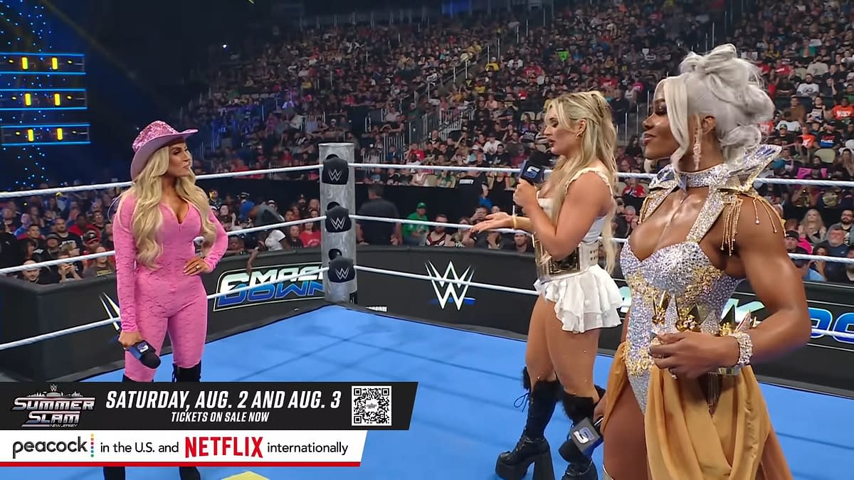 Trish Stratus, Tiffany Stratton, and Jade Cargill stand in a wrestling ring on WWE SmackDown, with a packed audience visible in the background. Each performer showcases distinctive outfits, with Stratus wearing a pink ensemble and a cowboy hat, Stratton in a white costume, and Cargill in a sparkling silver outfit.