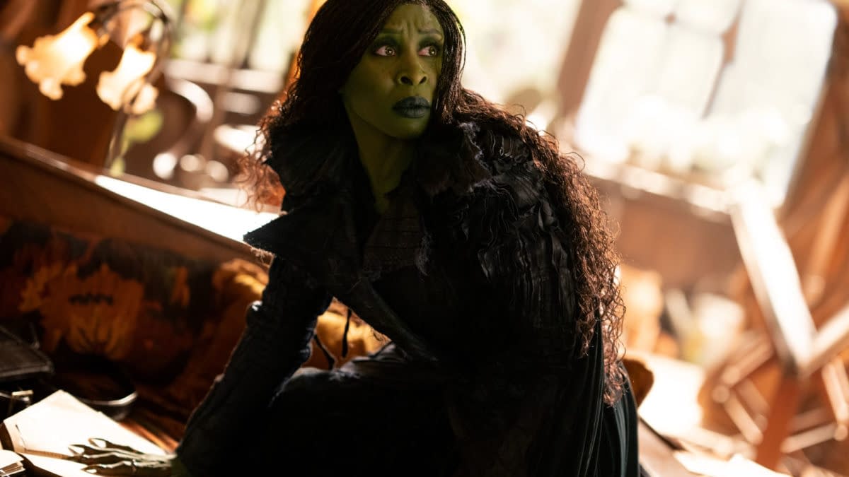 Cynthia Erivo portrays Elphaba in the film 'WICKED FOR GOOD,' wearing a dark, textured costume and exhibiting a serious expression in a richly decorated setting.