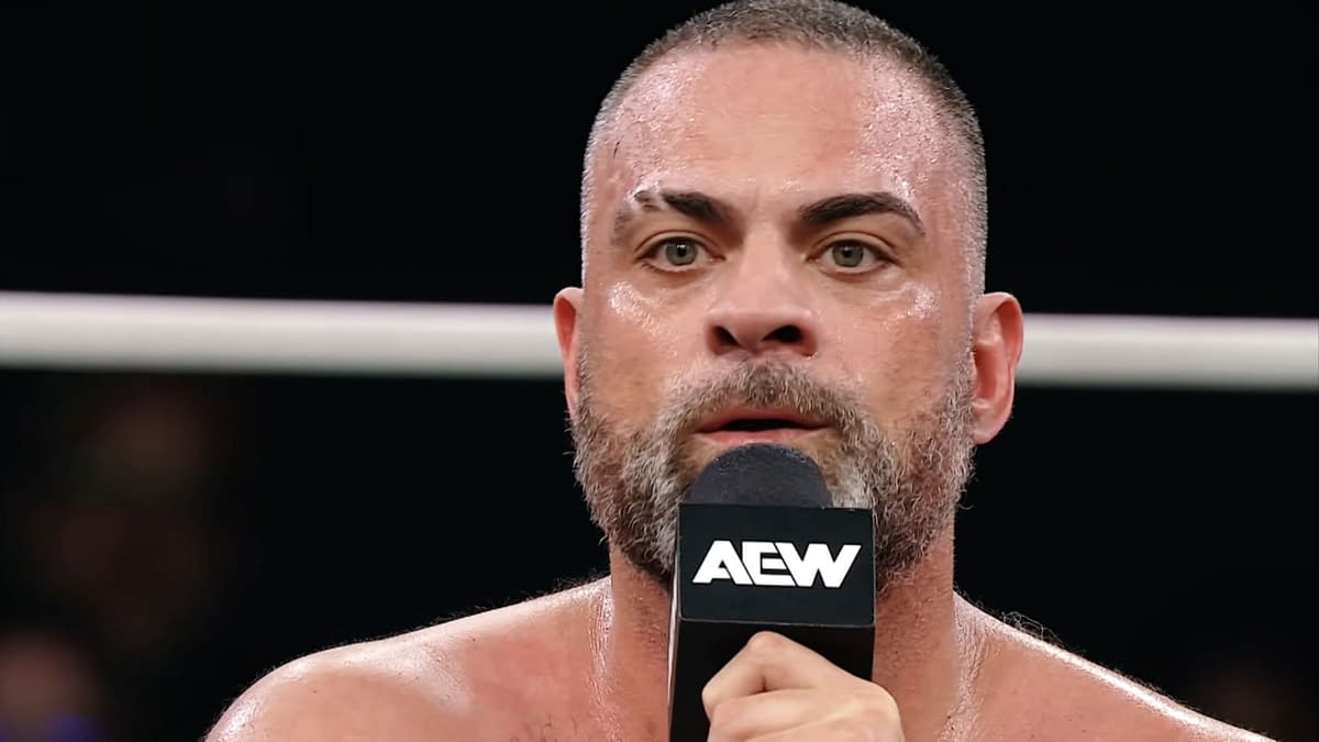 Eddie Kingston delivers an emotional promo in a wrestling ring, holding a microphone and appearing visibly intense and passionate.