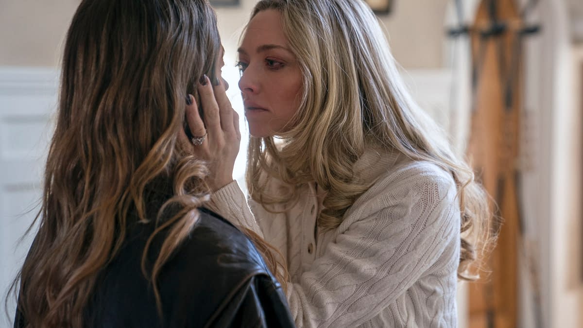 In a dramatic scene from 'The Housemaid,' Sydney Sweeney, portraying Millie Calloway, and Amanda Seyfried as Nina Winchester share an intense moment, framed against a softly lit interior with an emphasis on their emotional connection.
