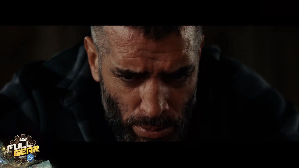 A close-up of Mark Briscoe's face, showing intense emotions, with a beard and a serious expression as he reflects before his TNT Championship match. The AEW Full Gear logo is featured at the bottom corner.