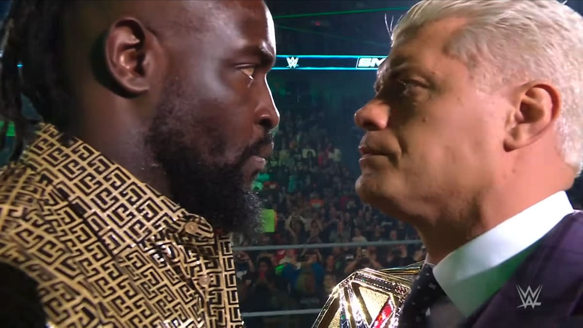 Oba Femi and Cody Rhodes engage in an intense face-off during WWE SmackDown, highlighting their upcoming match at Saturday Night's Main Event. The focus is on their determined expressions and body language.