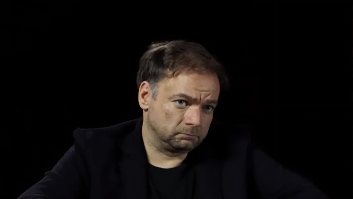 André Øvredal with short, slightly tousled hair and a serious expression is seated against a black background.