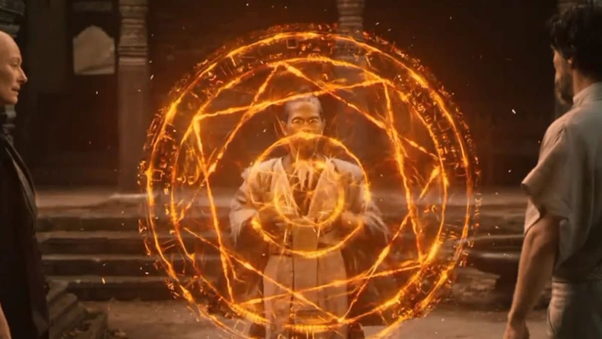 Doctor Strange’s Master Hamir stands inside a glowing orange magical shield, facing two other figures in a temple-like setting.