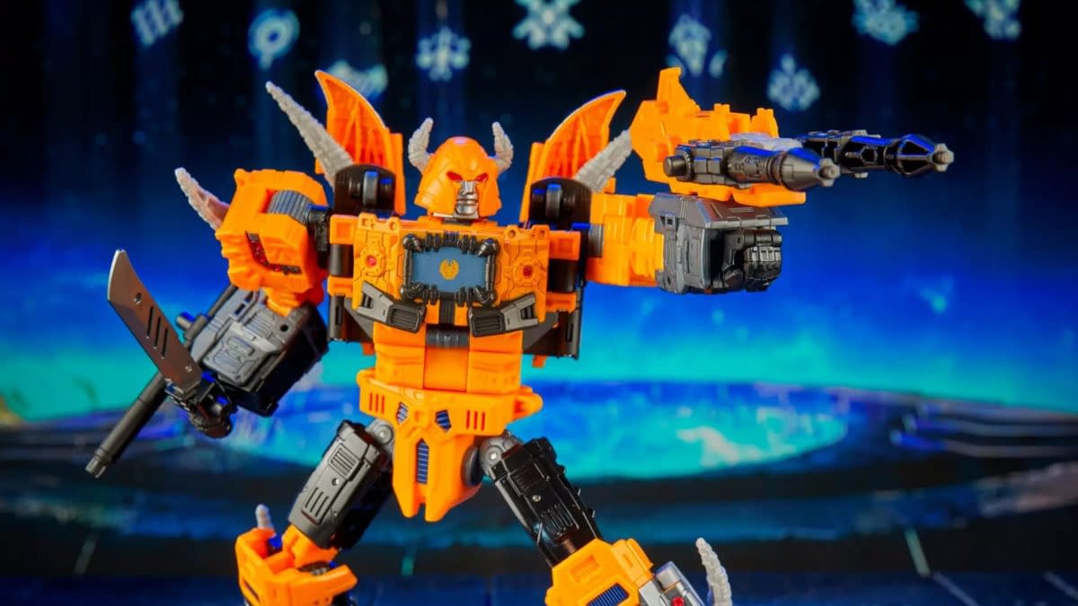 A Transformers action figure of Unicron's herald, orange and gray with horns and wing-like parts, posed with weapons against a blue sci-fi background.