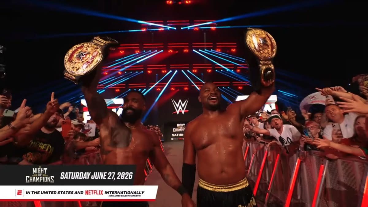 The Street Profits walk the WWE Raw entrance ramp in London, raising gold championship belts above a cheering crowd. Red and blue stage lights glow behind them.