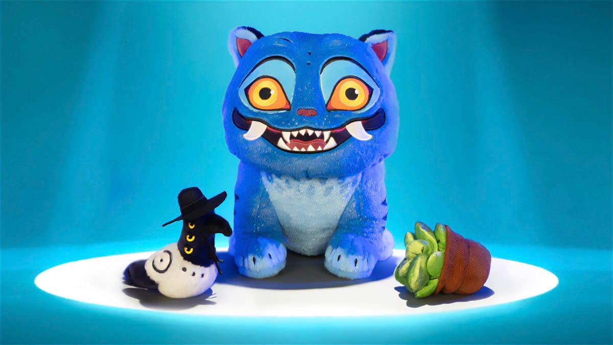 A blue Derpy Tiger plush from KPop Demon Hunters sits on a glowing display with two small companion figures. The plush has oversized eyes, sharp teeth, and a playful, cartoonish look.