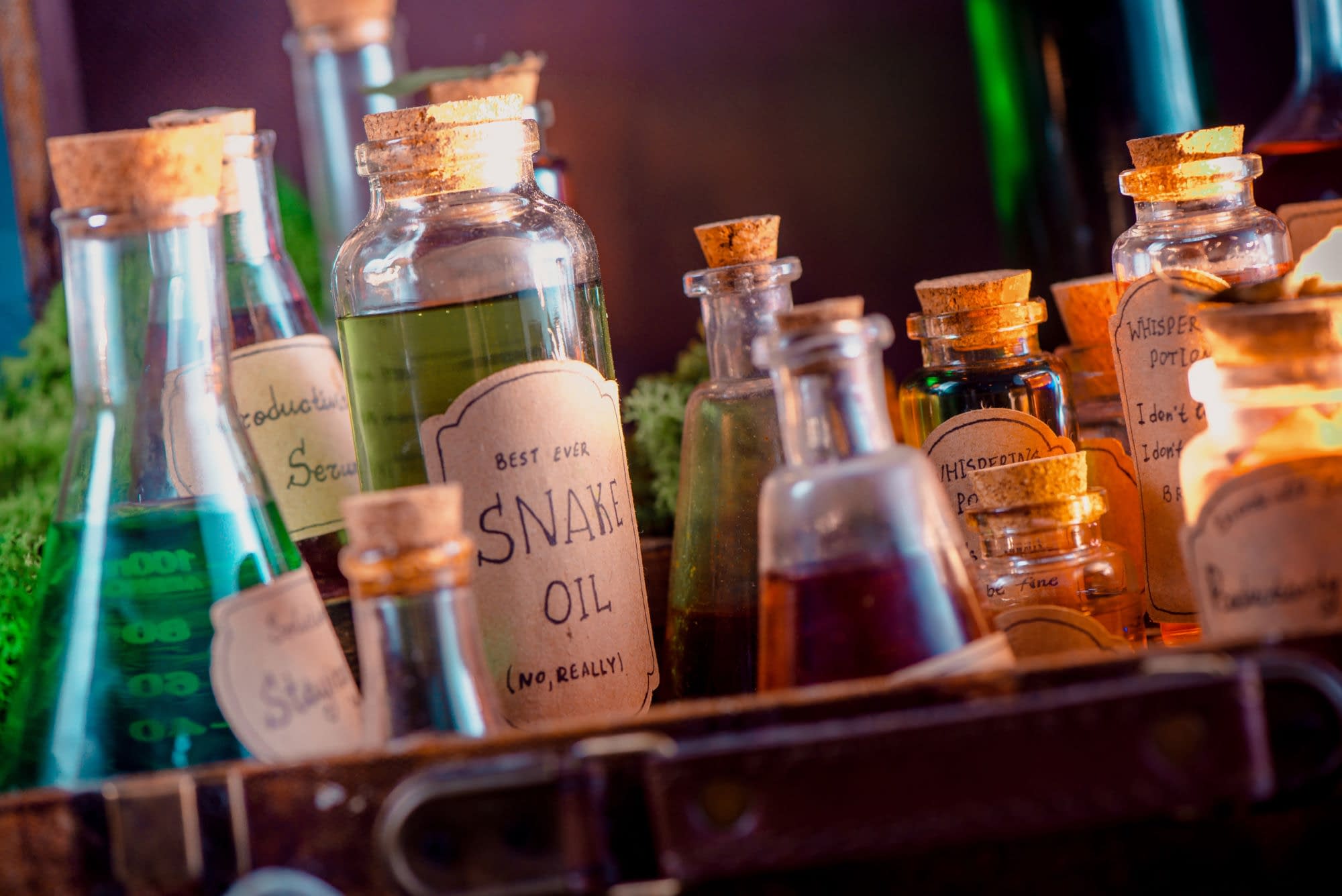 Glass bottles filled with colorful liquids are labeled as whimsical fake potions, including one marked