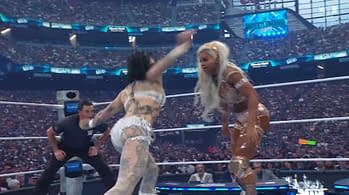 Two female wrestlers are in the ring, with one delivering a powerful strike while the other braces for impact, showcasing an intense moment during a match at WrestleMania. A large audience is visible in the background, adding to the excitement of the event.