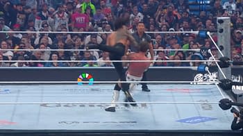 A wrestling match featuring a powerful kick from one wrestler to another, with a large audience in the background showing excitement and anticipation. The scene captures the energy and intensity of a championship event.