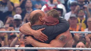 Two wrestlers embrace in a celebratory hug in the wrestling ring, surrounded by an enthusiastic crowd.