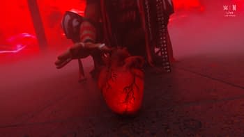 A stylized, glowing red heart is placed on the ground, surrounded by a misty atmosphere with a dramatic red lighting backdrop. A figure reaches toward the heart with an outstretched hand, adding to the intense ambiance.