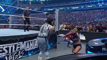 A wrestling match at WrestleMania, featuring two competitors in action by the ring. The audience is visible in the background, with excitement surrounding the event.