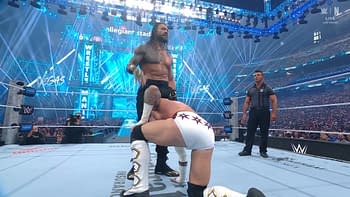 A professional wrestling scene during WrestleMania featuring Roman Reigns, who towers over an opponent on the mat, amidst a vibrant arena filled with lights and fans.