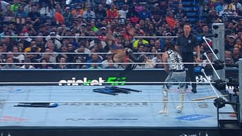 A professional wrestling scene with a high-flying athlete performing a move in the ring. The audience is engaged and excited, with a mix of fans visible in the background.