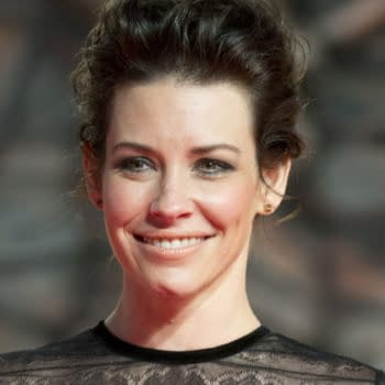 Evangeline Lilly smiles at the premiere of 'The Hobbit: The Desolation of Smaug' in Berlin, wearing a black lace dress. The image captures her at the event held on December 9, 2013, highlighting her as a notable celebrity in the movie industry.