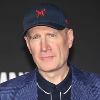 Kevin Feige poses on a red carpet event in Los Angeles, wearing a navy baseball cap with a red Spider-Man logo and a blue jacket.