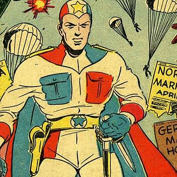 A superhero, The Conqueror, stands confidently with a star emblem on his chest, holding weapons. Behind him, parachutes drop from planes amidst newspaper headlines about wartime events.