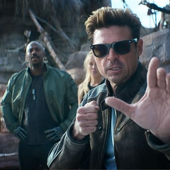 A scene from 'Mortal Kombat 2' featuring a group of diverse characters, with one man in the foreground wearing sunglasses and striking a fighting pose, while others observe in the background.