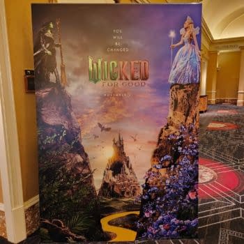 A promotional banner for the musical 'Wicked' featuring dramatic illustrations of a witch and a fairy princess, set against a mystical landscape with a castle and vibrant flowers. The banner includes the text 'YOU WILL BE CHANGED' and 'WICKED FOR GOOD' with a release date of November 21.