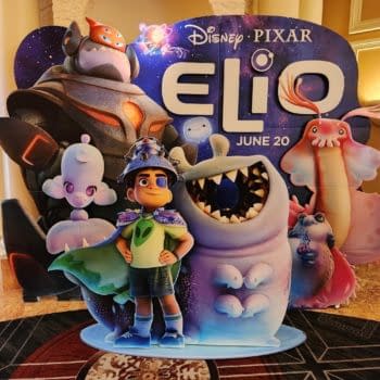 A colorful display featuring characters from the Disney Pixar film 'Elio'. In the foreground, a young boy wearing a green shirt and a blue cape stands confidently next to various whimsical extraterrestrial creatures.