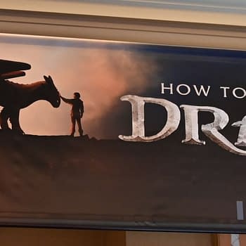 A promotional banner for 'How to Train Your Dragon,' featuring a silhouetted dragon and a young character standing together against a dramatic sunset backdrop. The words 'HOW TO TRAIN YOUR DRAGON' are prominently displayed, along with the release date 'JUNE 13' and the note 'FILMED FOR IMAX.'