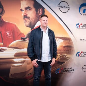 A man poses on the red carpet at a special screening for the movie 'Gran Turismo: Based on a True Story' in Barcelona, Spain. Behind him are prominent promotional images from the film, showcasing race cars and characters.