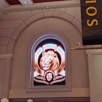A glowing MGM lion logo displayed in an arched frame inside a theater setting. Below the lion image, additional artistic elements are included, enhancing the classical theme.