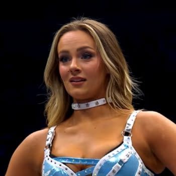 A female wrestler, Anna Jay, stands in the ring wearing a blue and silver wrestling outfit. She has long hair and appears to be waiting for her opponent, Penelope Ford, after her return at AEW Collision.