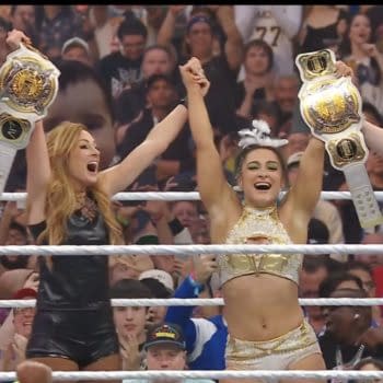 Becky Lynch and Lyra Valkyria celebrate winning the tag titles at WrestleMania 41, raising their championship belts in the air with excitement. The energetic crowd surrounds them during this triumphant moment.