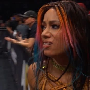 Mercedes Moné shows her disappointment after losing a tag match, with visibly upset expressions. The audience is slightly blurred in the background, depicting the atmosphere of a wrestling event.