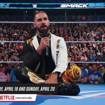 Seth Rollins, wearing a striking black and white outfit adorned with floral patterns, sits on the wrestling ring while delivering a promo during WWE SmackDown, with a large audience in the background.