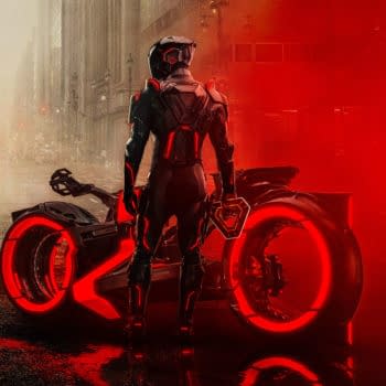 A dramatic illustration from 'TRON: Ares' featuring a futuristic figure in a sleek, black outfit, standing beside a high-tech motorcycle with glowing red accents, set against a foggy urban backdrop.