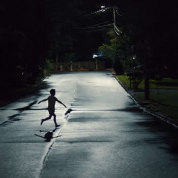 A silhouette of a child running down a dimly lit street at night, with streetlights illuminating the wet pavement.