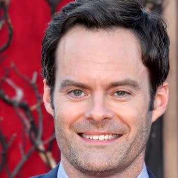 Bill Hader smiles at the premiere of "IT Chapter Two" in Los Angeles, showcasing a friendly demeanor against a red and earthy backdrop.