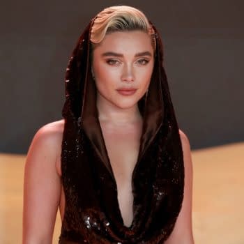Florence Pugh is seen in a glamorous outfit featuring a hooded design, showcasing her striking features and makeup at a fashion event in London.