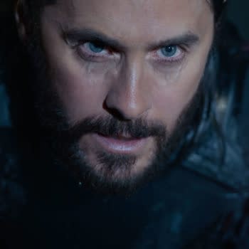 Jared Leto portrays Ares in a close-up shot from Disney's live-action film TRON: ARES, featuring dramatic lighting and a futuristic costume with red accents.