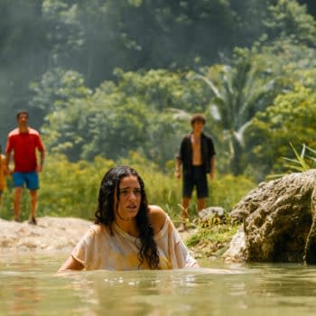 Still from 'Jurassic World Rebirth', featuring Isabella Delgado wading in water, looking concerned, while Reuben Delgado, Teresa Delgado, and Xavier Dobbs stand in the background, surrounded by greenery.