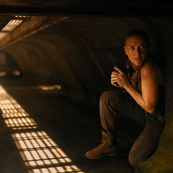 A woman crouches in a dimly lit environment, holding a handgun. She appears alert and focused, suggesting a scene of suspense from 'JURASSIC WORLD REBIRTH.'