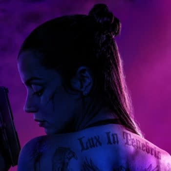 A woman with long, dark hair styled in a bun poses with a gun, her back to the viewer. Her tattooed shoulder features the phrase 'Lux In Tenebris,' while dramatic purple lighting creates a moody atmosphere.